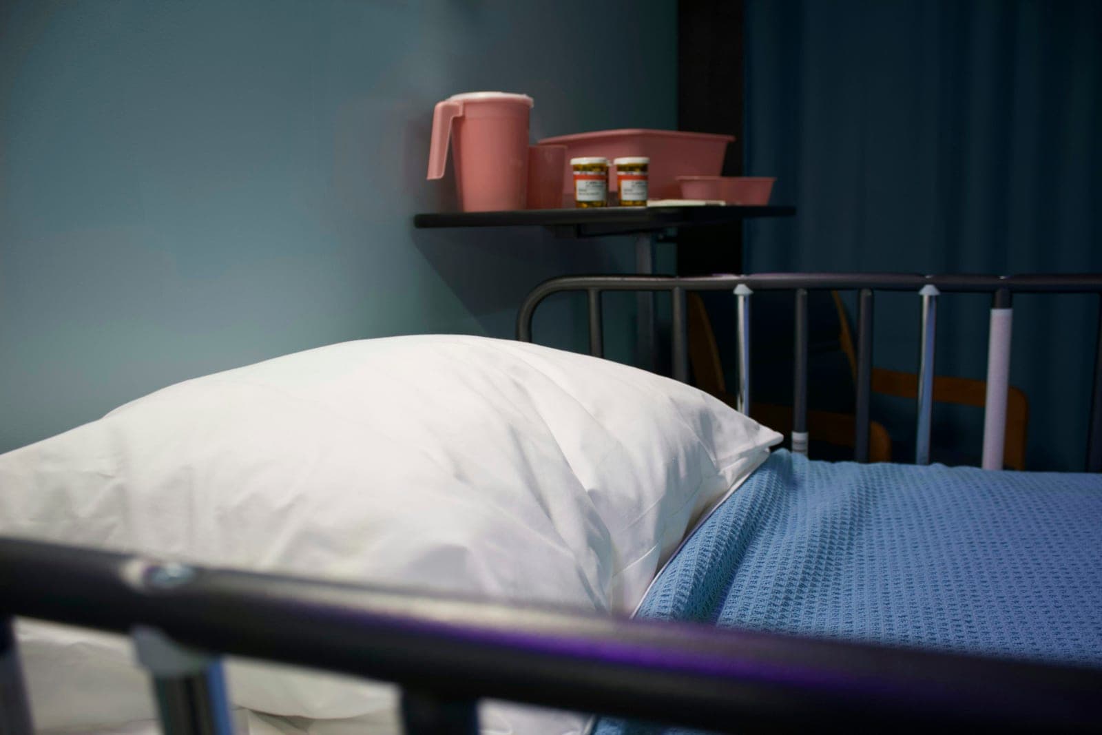 Ein weißes Kissen und eine blaue Decke auf einem Krankenhausbett
