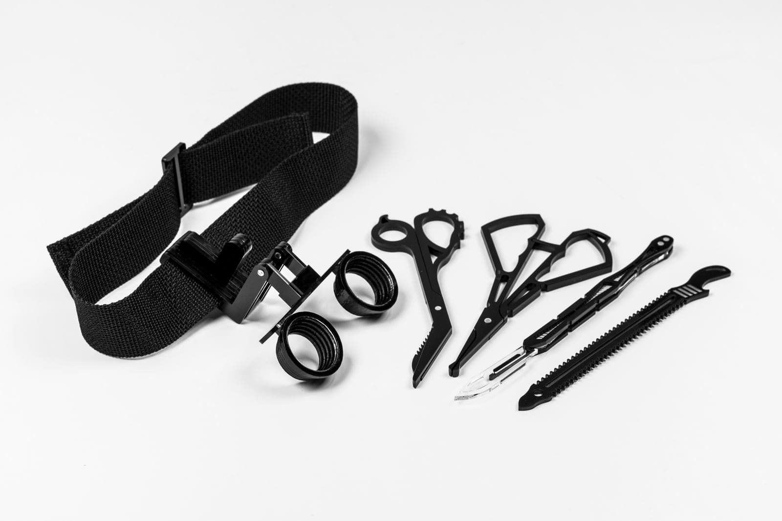 Ein Kopfband mit Lupen und schwarze chirurgische Instrumente auf weißem Untergrund