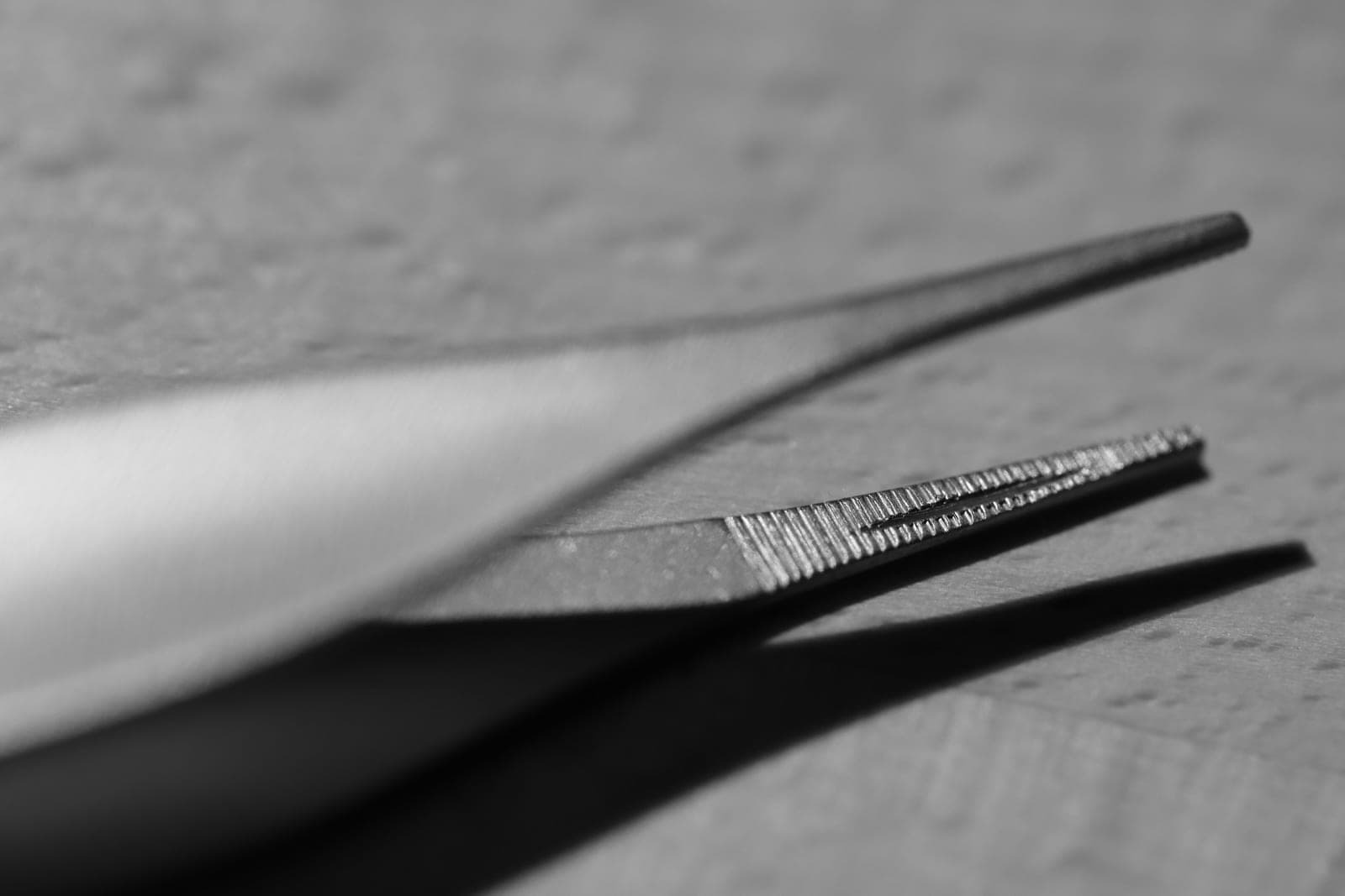 Gros plan sur une pince métallique aux extrémités striées, en noir et blanc