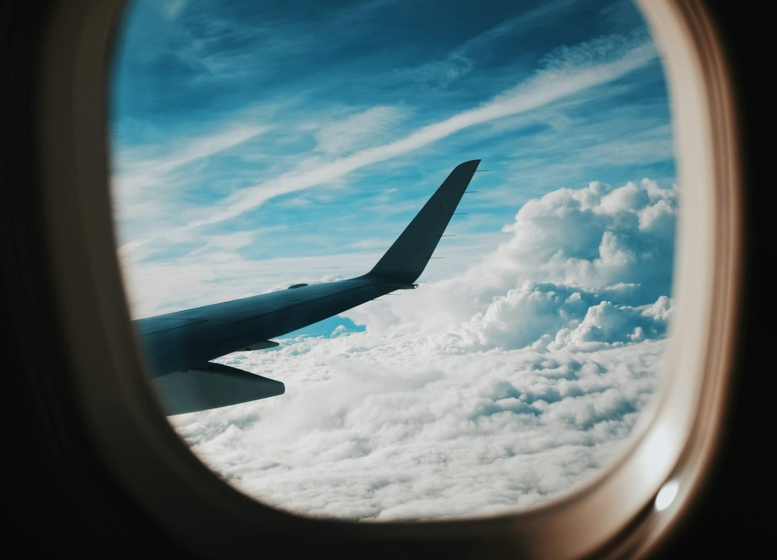 Eine Flugzeugtragfläche über den Wolken, durch das Fenster gesehen