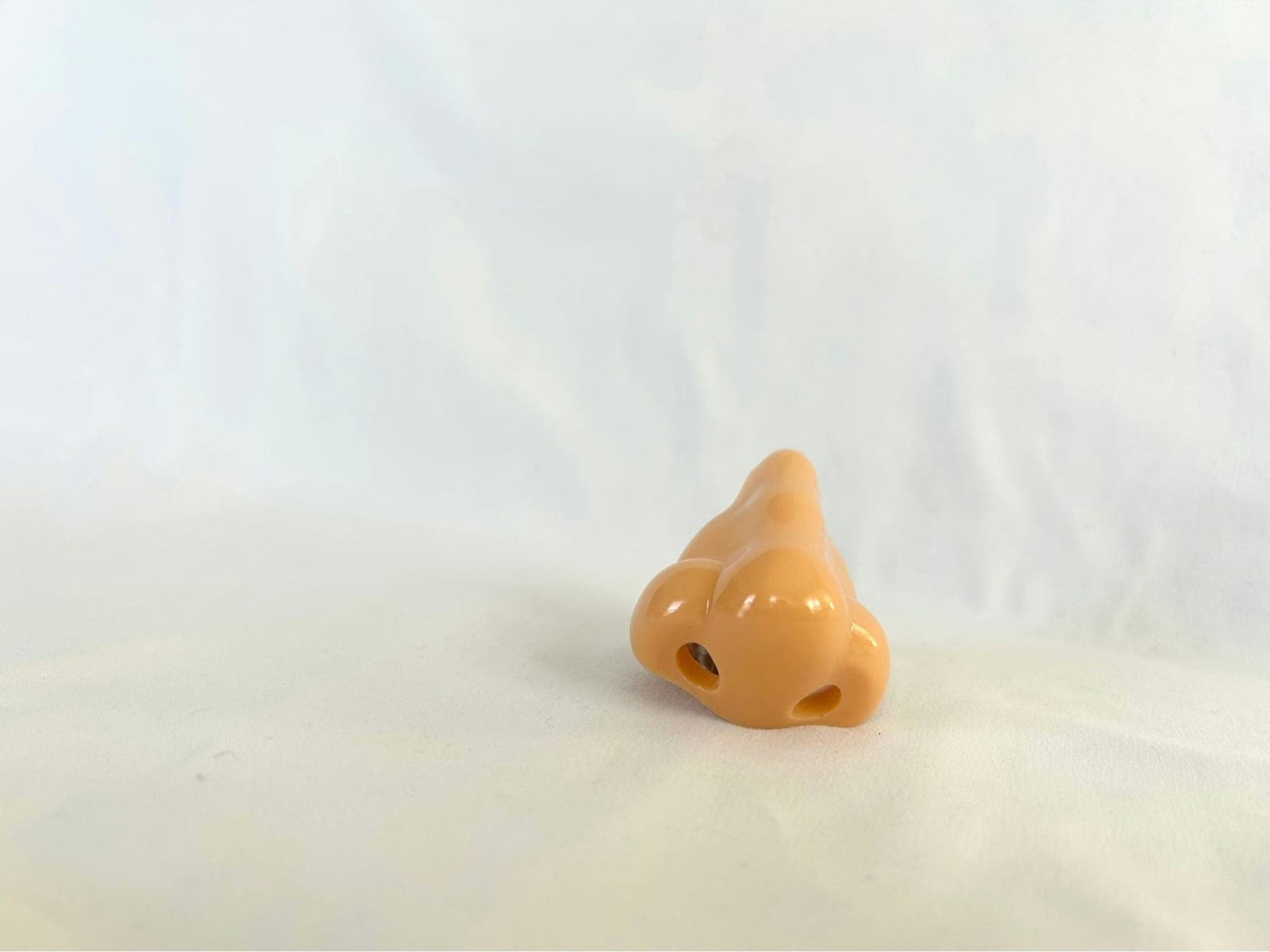 Eine hautfarbene Nasenfigur aus Kunststoff auf weißem Stoff