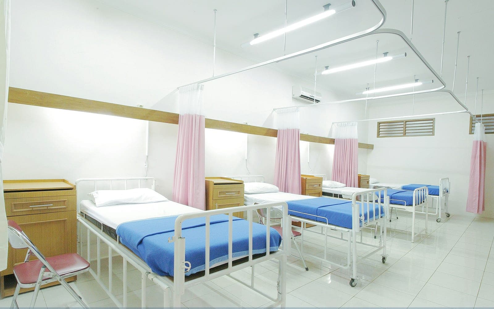Une salle d’hôpital aux lits vides séparés par des rideaux
